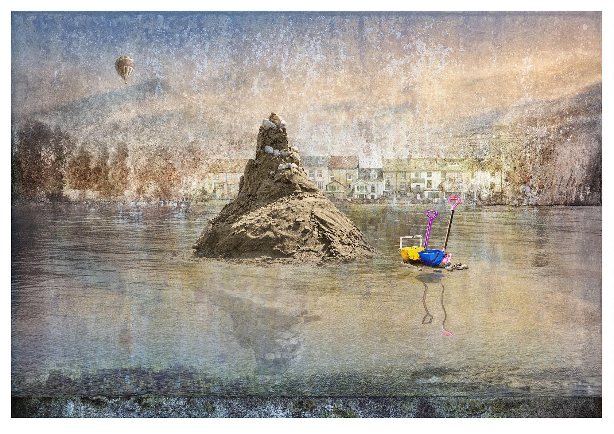 Tall roughly hewn sand castle, sits in wet sand beach with childrens bucket and spade. Warm textured overlay